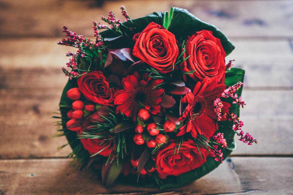 A bouquet of bright red flowers on a wooden table